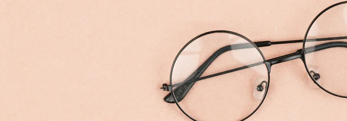 Black framed glasses on a pink background.