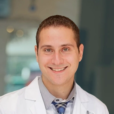 Dr. Lev Mazniker smiling in a white coat.